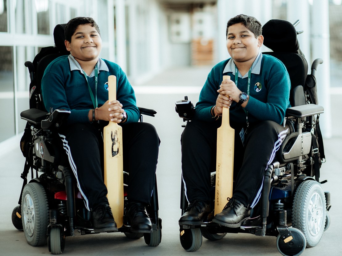 Twin Sri Lankan boys in wheelchairs holding cricket bats