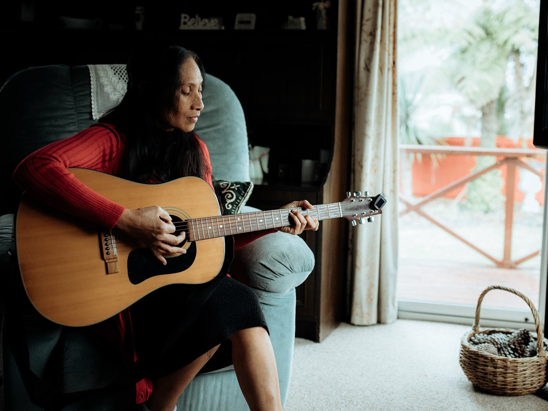 Pasifica woman with vision impairment is playing a guitar