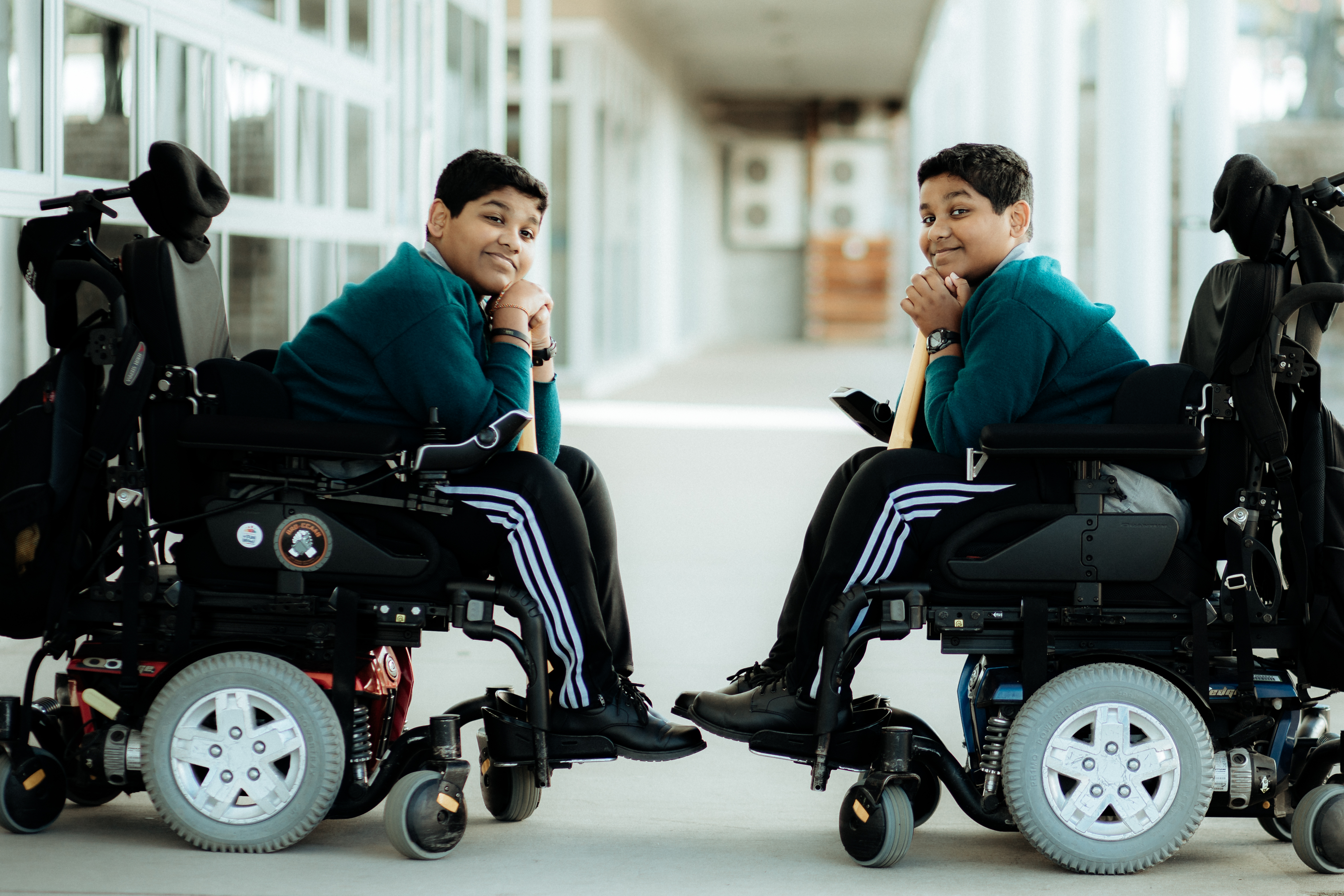 Sri Lankan twin boys in wheelchairs resting their chins on a cricket bat