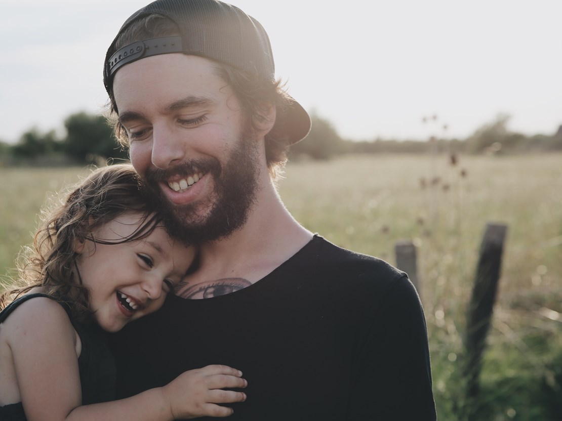 Dad and daughter cuddle under the sun