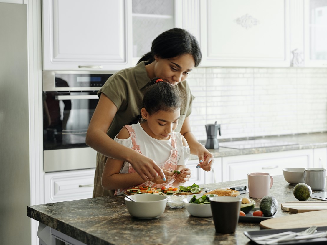 Mother helping young daugther prepare sandwich.jpg