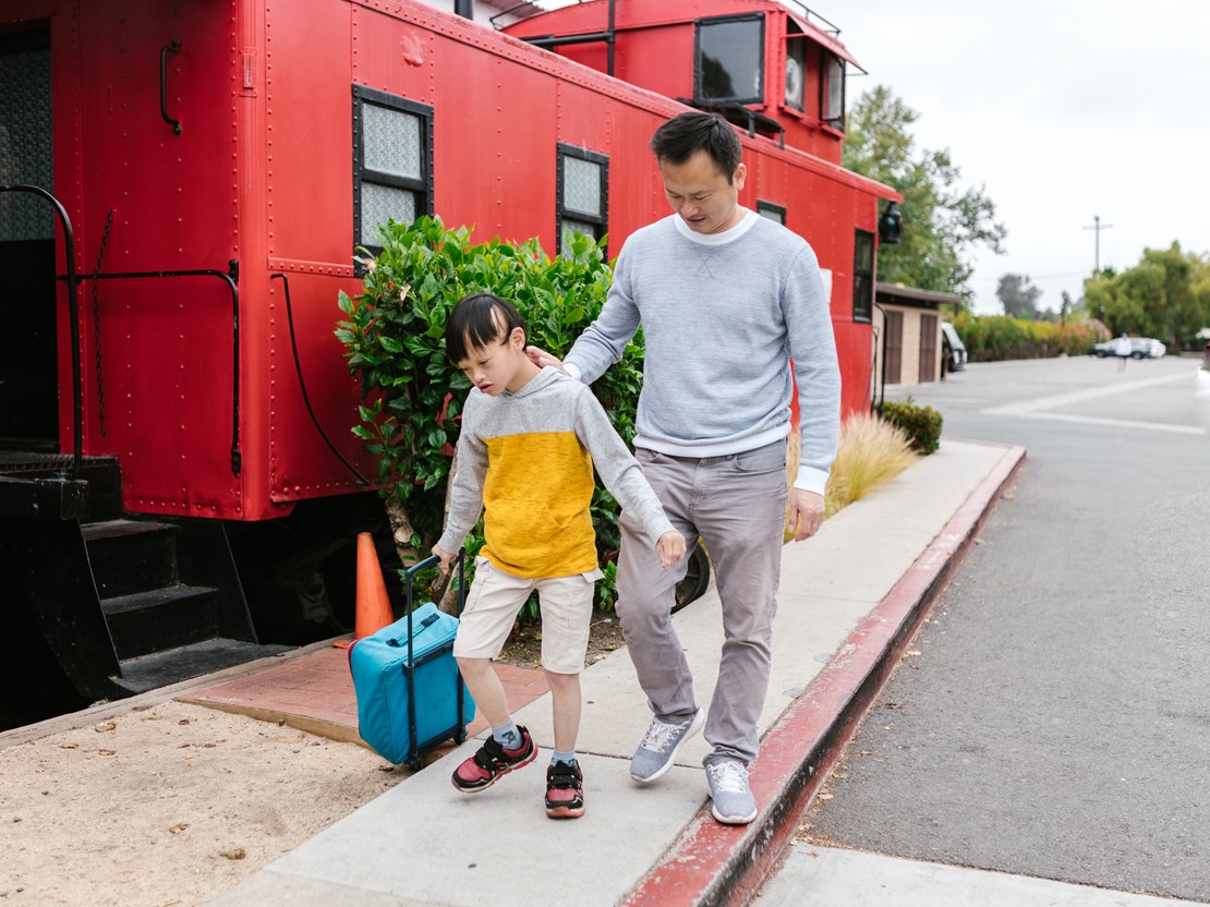 Young boy pulling a school walks to school with his father.jpg